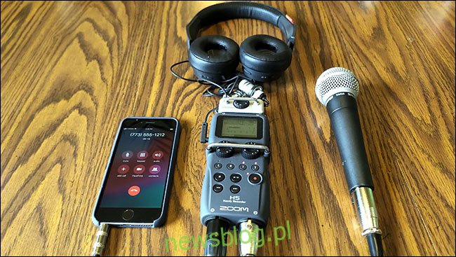 IPhone, mikrofon Shure SM58 i słuchawki podłączone do rejestratora H5 Zoom, leżącego na stole.