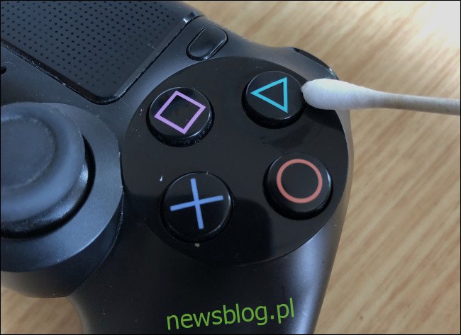 Q-tip wycierający przycisk na kontrolerze DualShock 4. 