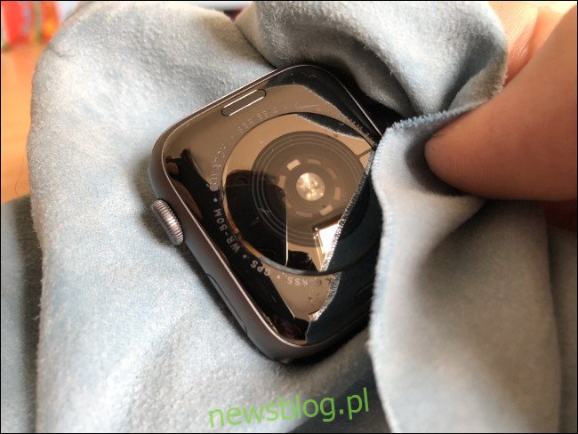 Ręka wycierająca Apple Watch szmatką.