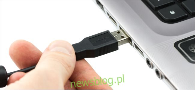 Ręka podłączająca kabel USB typu A do laptopa.