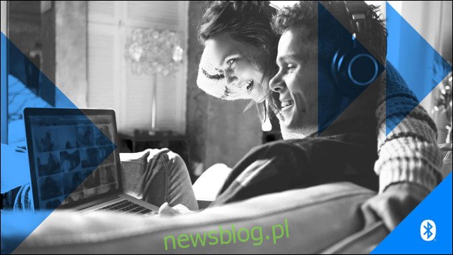 Mężczyzna i kobieta noszenie słuchawek, patrząc na ekran komputera przenośnego.