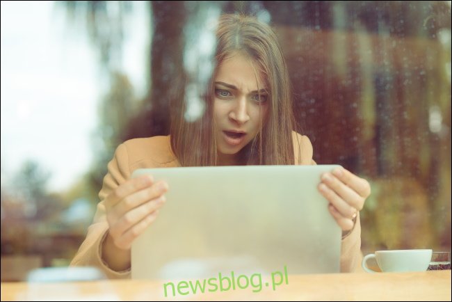 Zszokowana kobieta trzymająca ekran swojego laptopa.