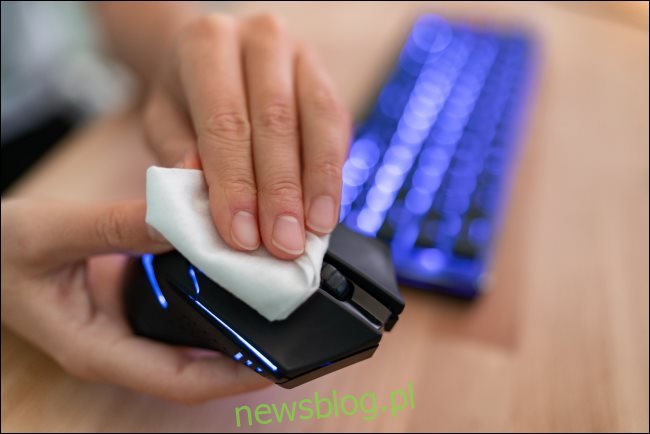 Ręka wycierająca mysz komputerową szmatką.