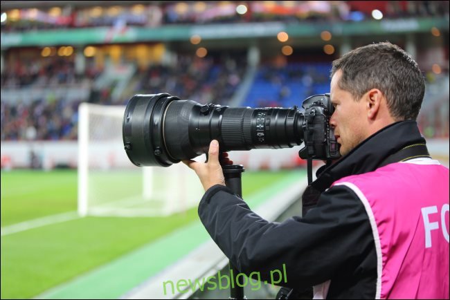 Fotograf z dużym obiektywem z zoomem optycznym na meczu piłki nożnej.